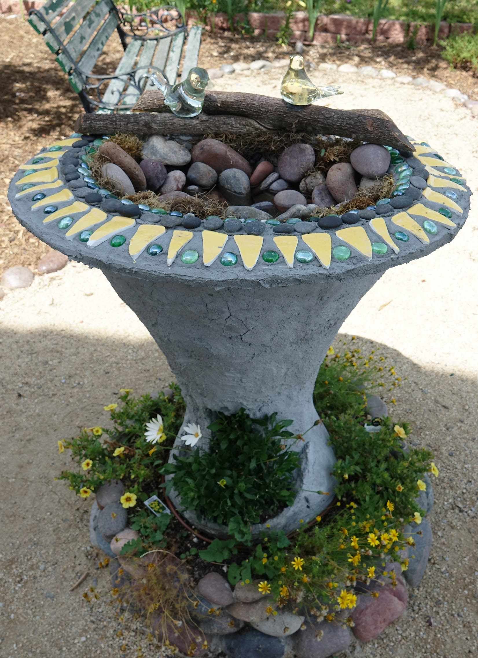 The top of the birdbath is decorated with pieces from a broken dish. 